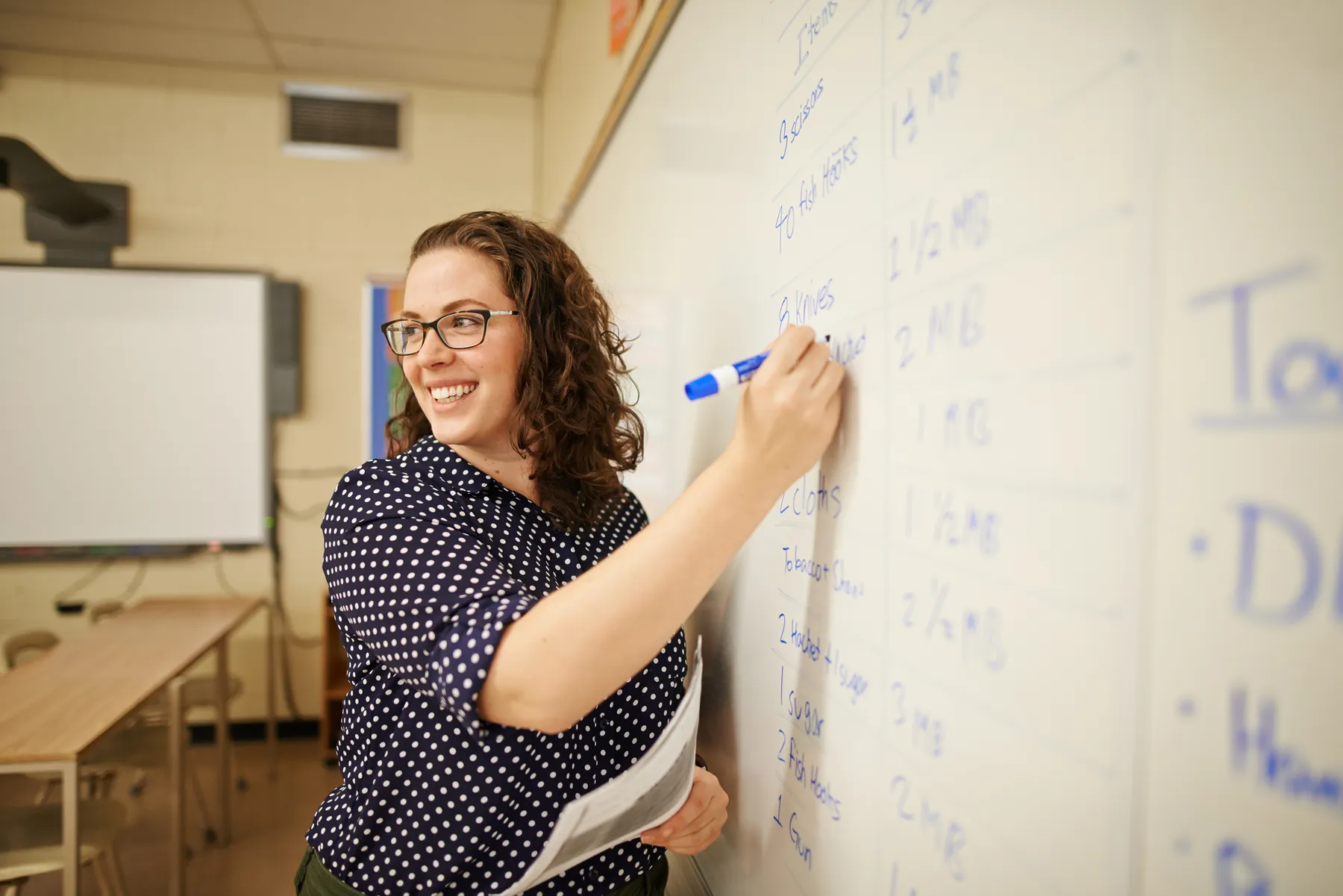 An AVRO Academy teacher writing on a whiteboard while teaching a class in midtown Toronto