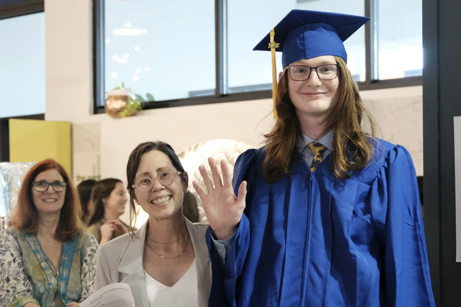 An AVRO Academy graduate waving with staff at graduation