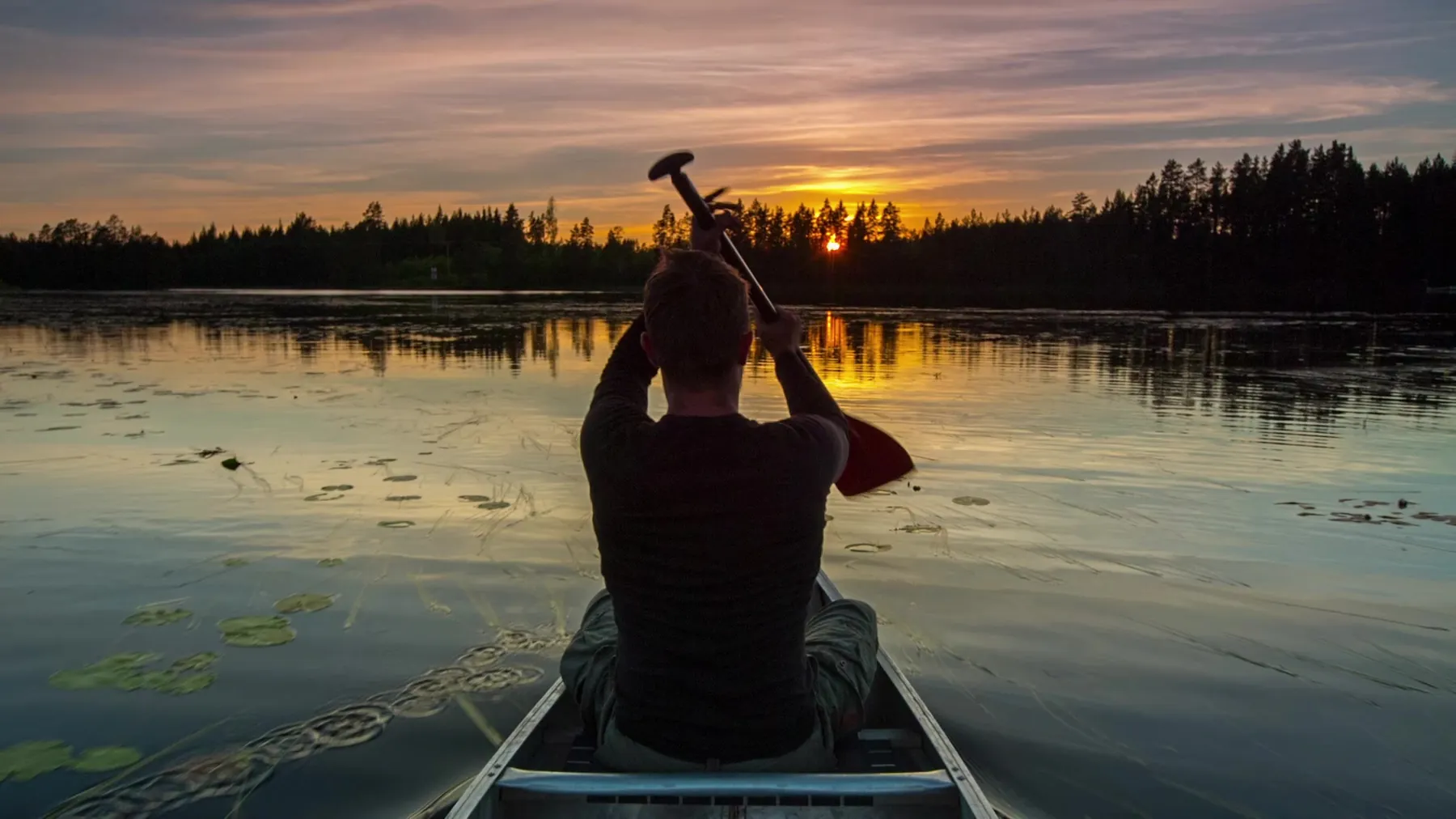 A person paddling a canoe at sunset on an outdoor leadership experience