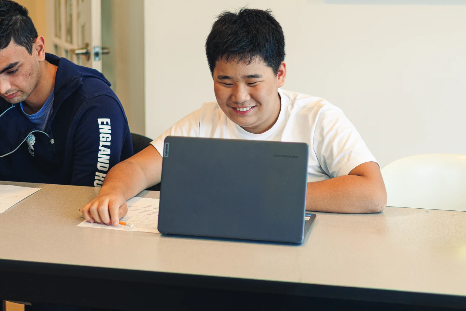 An AVRO Academy student learning on a laptop with staff support