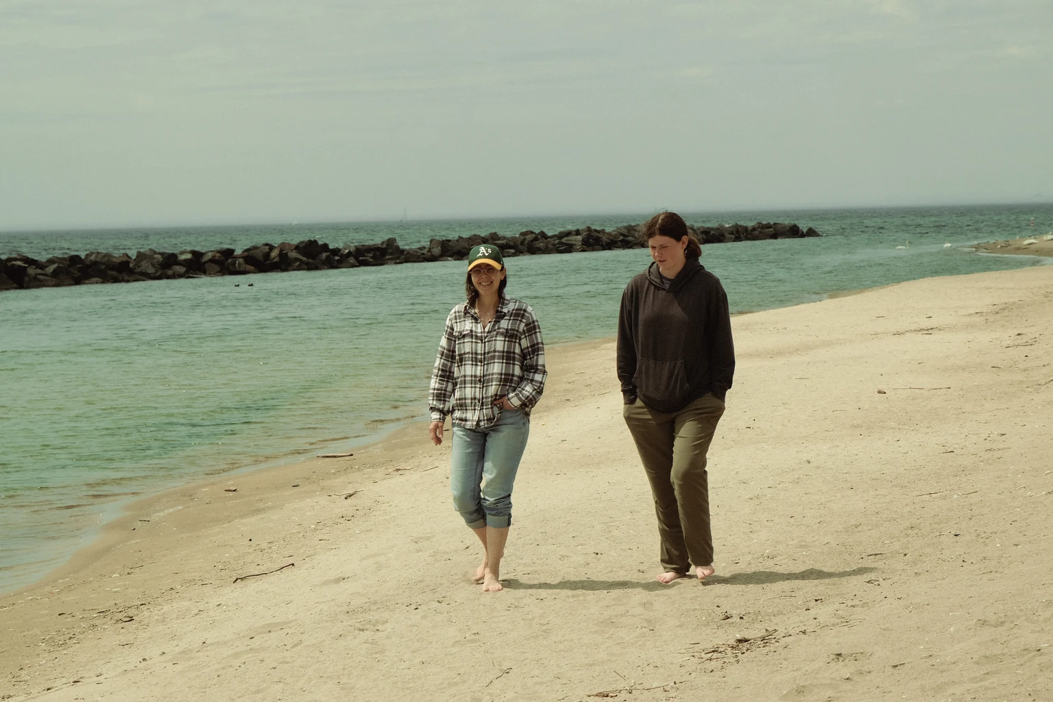 Two people walking together along the shoreline, calm and reflective